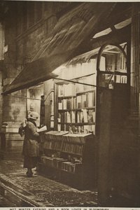 Esaminare un libro fuori da una libreria di seconda mano in una sera d